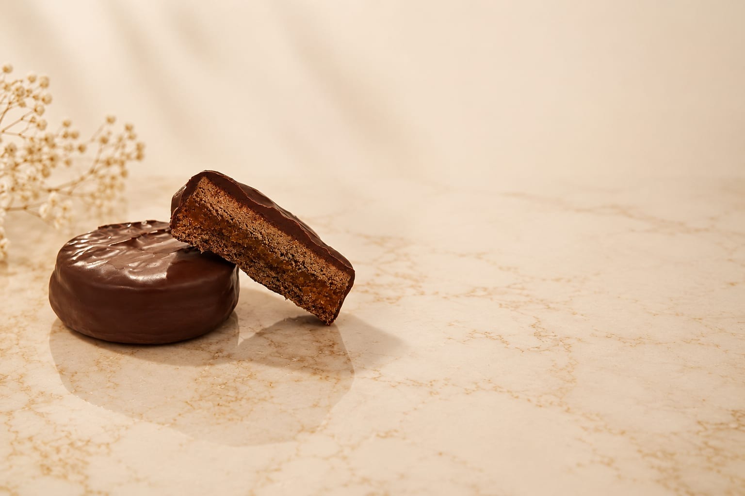 Alfajor PETRA Negro cortado al medio, con relleno de dulce de leche y chocolate